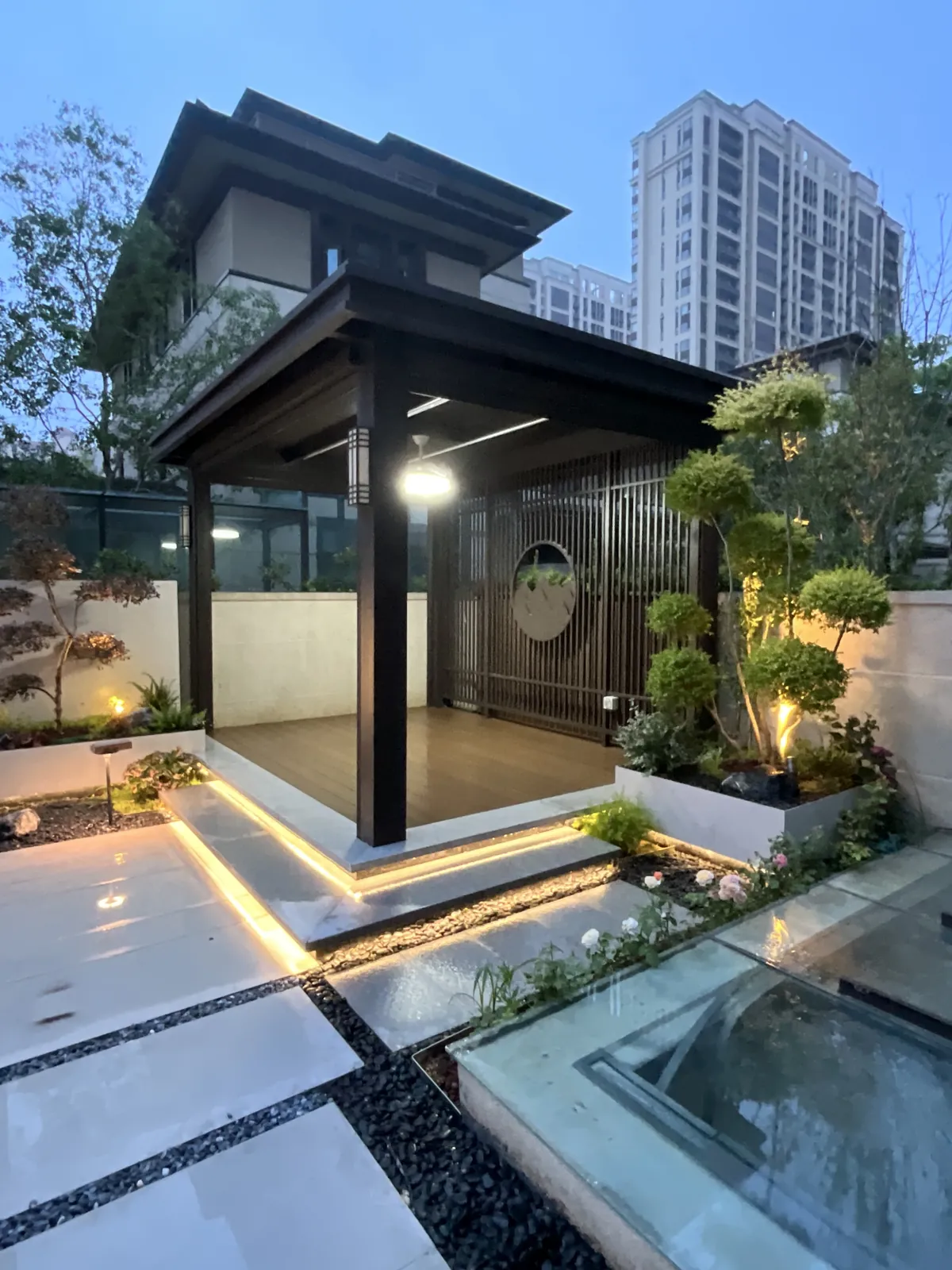 郑州兰乔圣菲完工实景:转角休闲亭采用深色框架,平台边缘灯带标出高差。