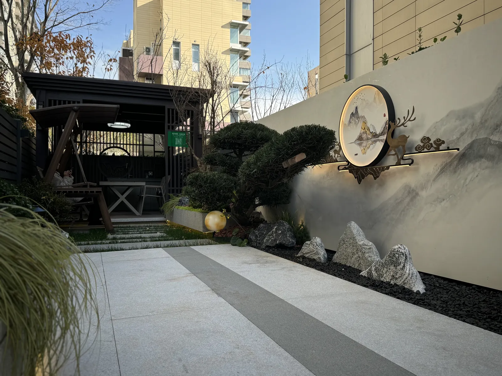 永威上和郡庭院山水景墙完工实景，圆形山水画、鹿形装饰、造型松和景石组合