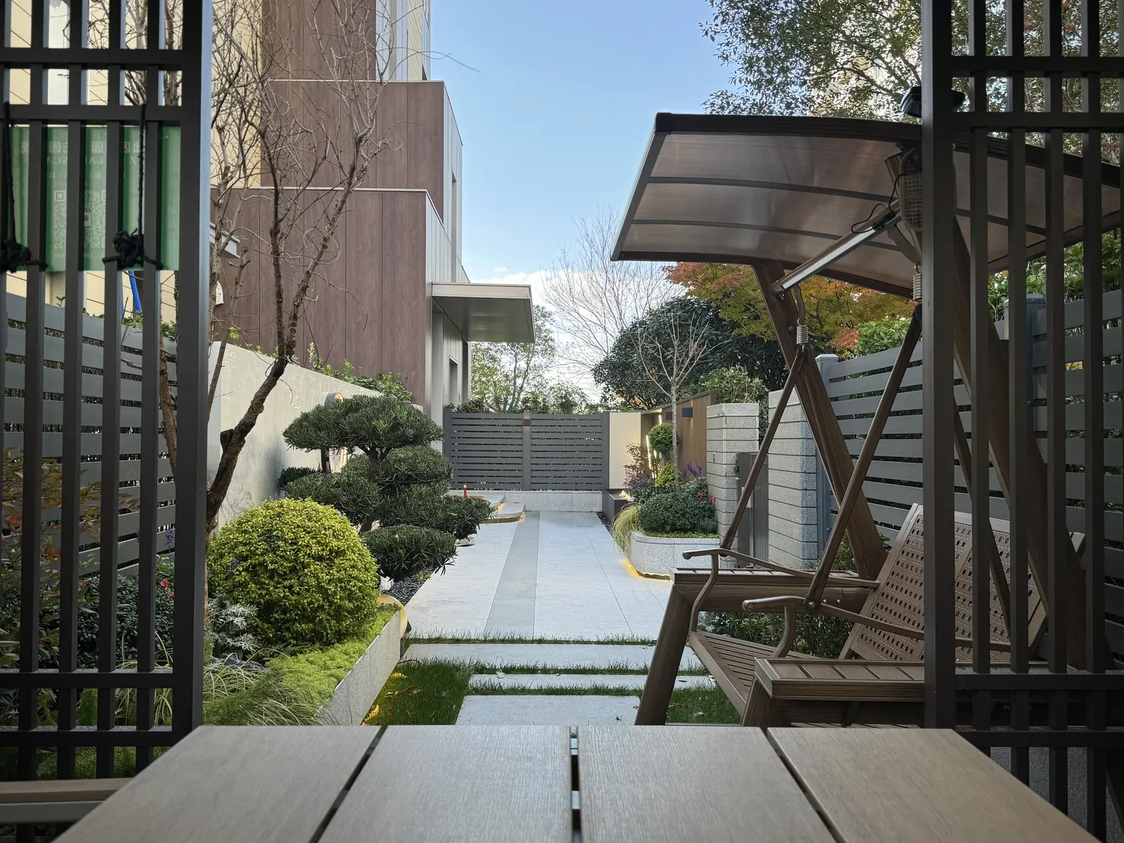 永威上和郡完工实景：廊架内回望入口：桌椅、秋千与草缝踏步连接花园主通道。